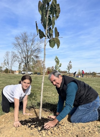 Board member and student plant tree 